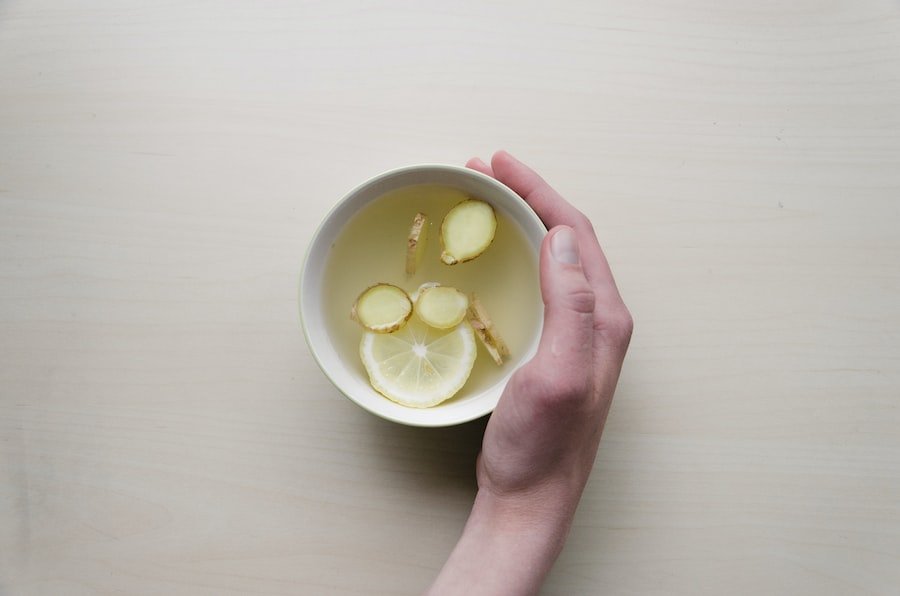 mano agarrando un cuenco con agua de limón y gengibre