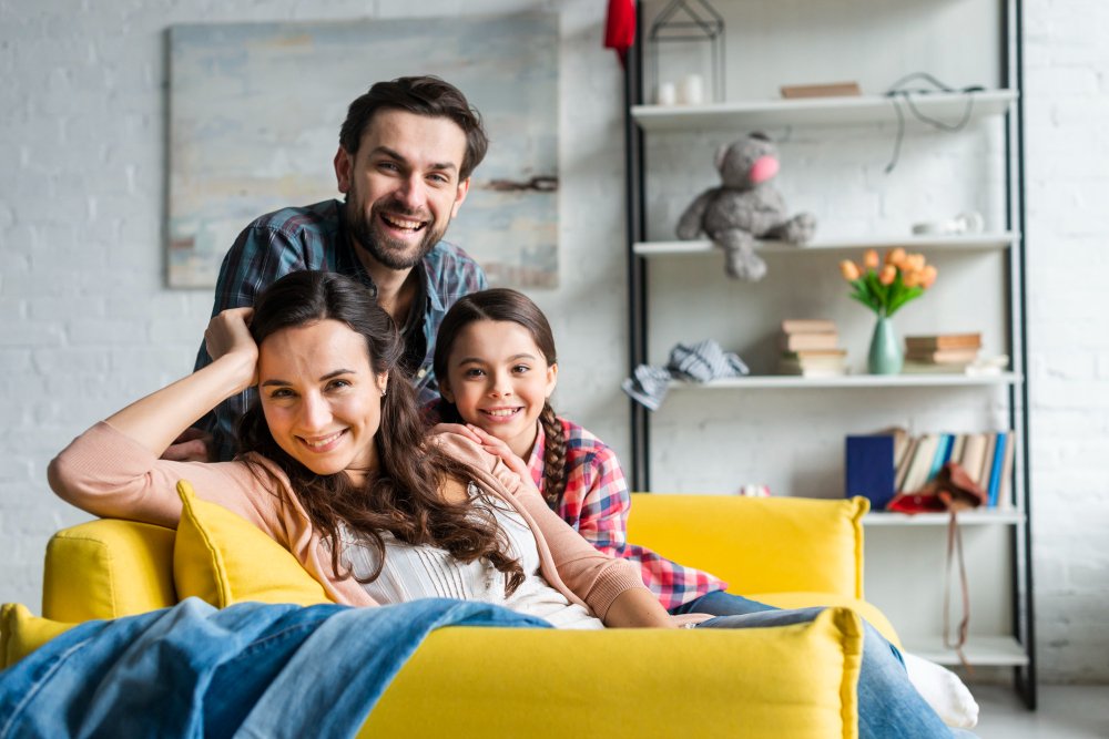 Familia feliz sentada en un sofá, no saben el impacto social de la ia