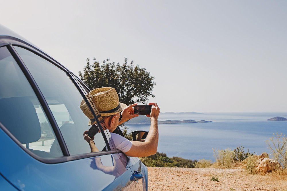 hombre tomando una foto con un teléfono inteligente desde la ventana abierta de un automóvil